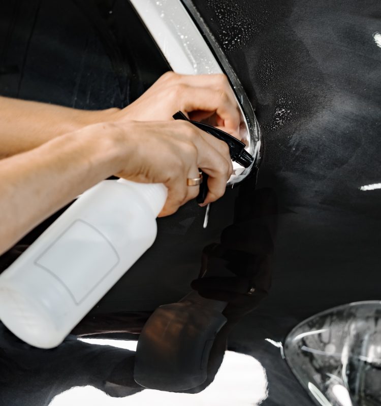 Car wrapping specialist wraps a car with adhesive film in car detailing service