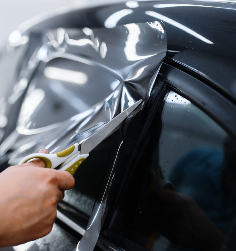Worker holds film, car tinting installation